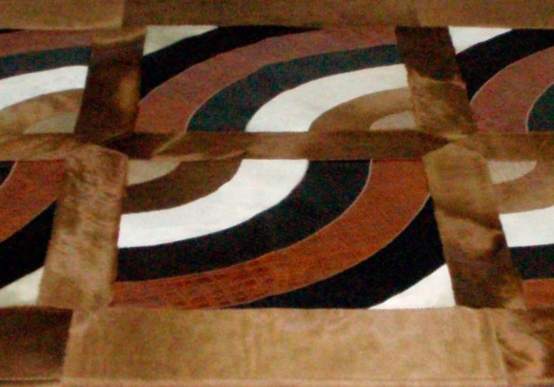 Particolare di tappeto in cavallino color champagne con disegni semicircolari in abete stampa cocco, stampa treccia e colori vari